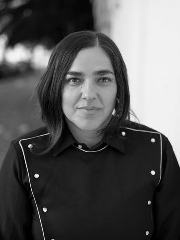 Josette Melchor against a white wall, direct gaze, black and white.