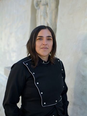 Josette Melchor, hand in pocket, before a plaster sculpture.