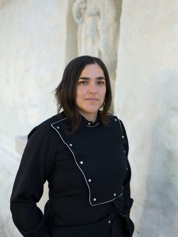Josette Melchor before a plaster sculpture, looking to camera.
