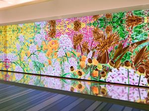 A large LED wall of generative floral artwork from Google's Gradient Canvas collection, mirrored on a polished floor.