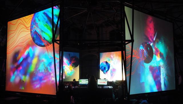 The ISM Hexadome — large suspended screens surrounding the audience, washed in vivid projected color.