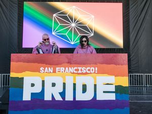 Josette Melchor and John Major (JMxJM) DJing behind a rainbow San Francisco Pride booth on the main stage.