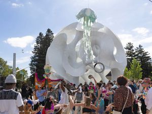A crowd dancing beneath a large white sculptural pavilion at a Google public activation.